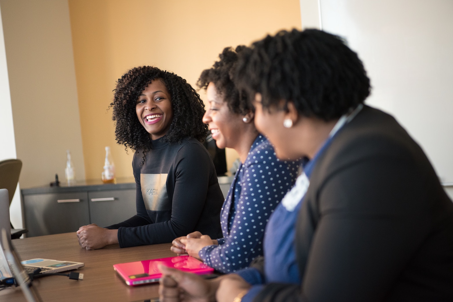 Three women sitting together at a conference table.