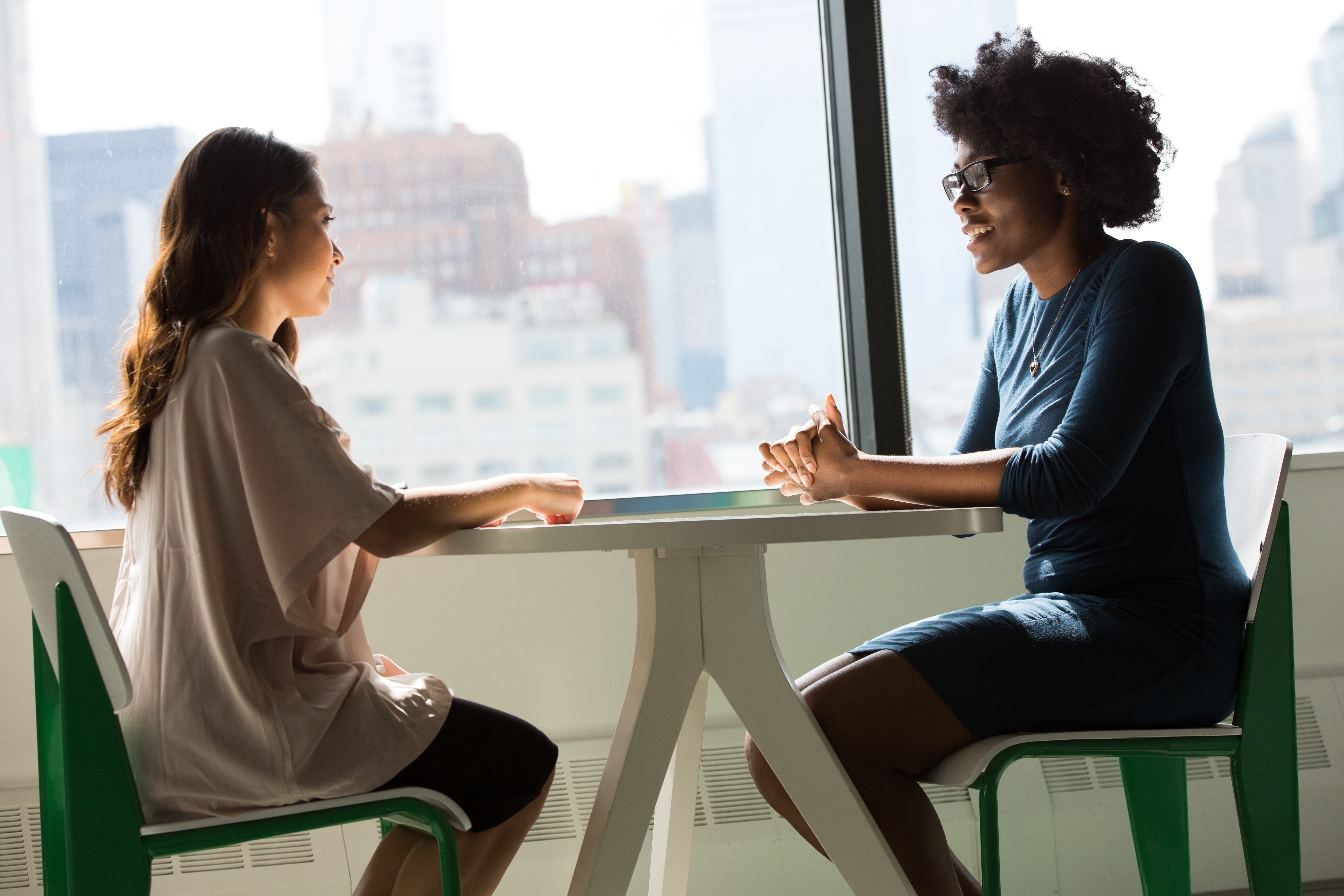 Photo of two women sitting at a table in front of a window.