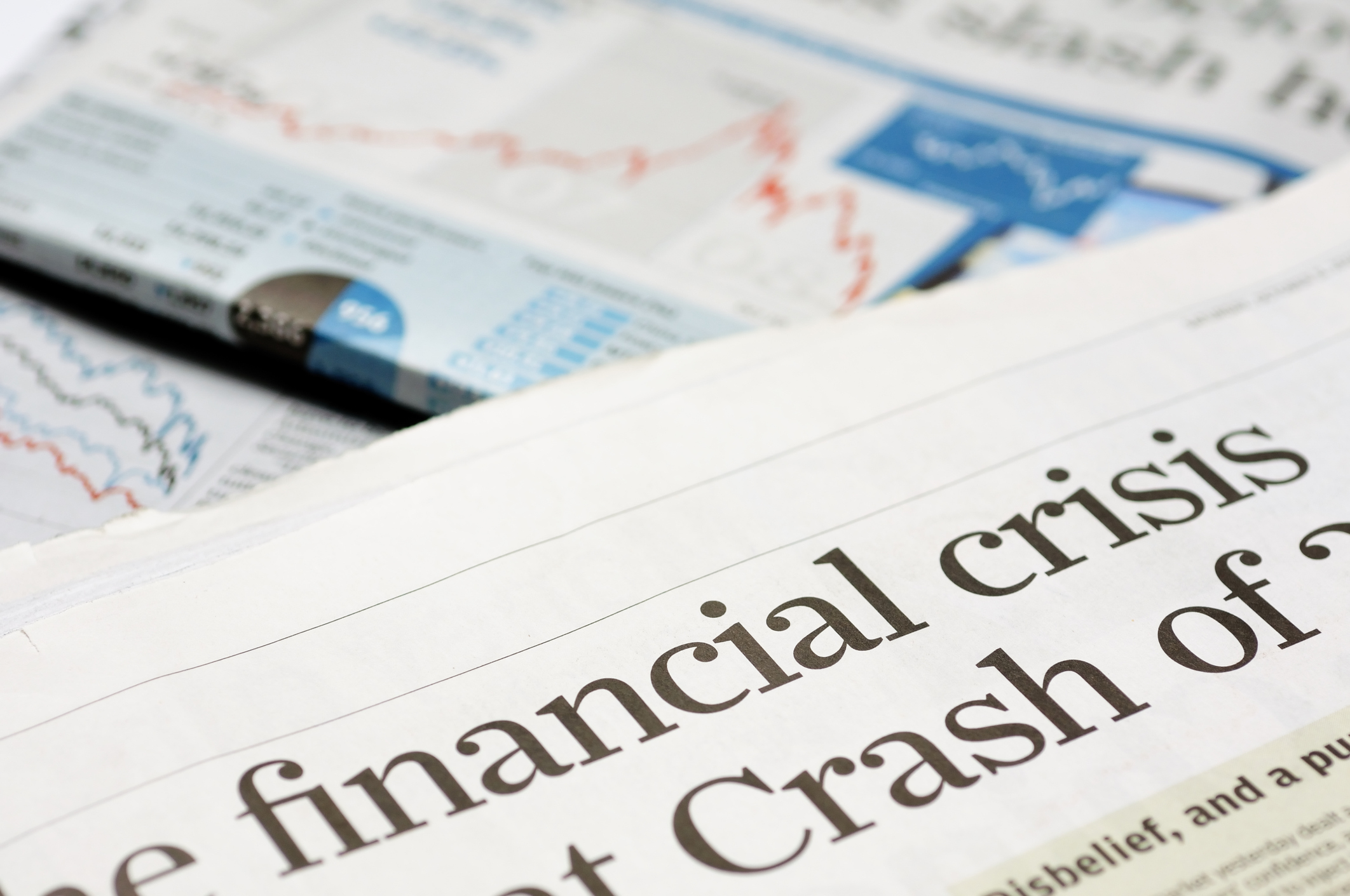 Partial view of newspaper with words reading "financial crisis" and "crash" in the headline